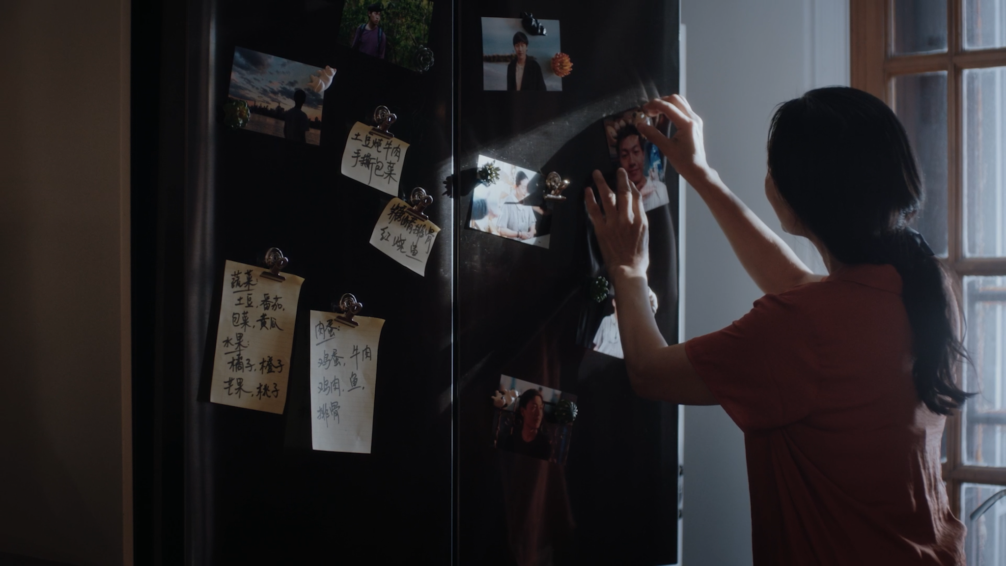 A woman arranging family photographs in a still from Alone